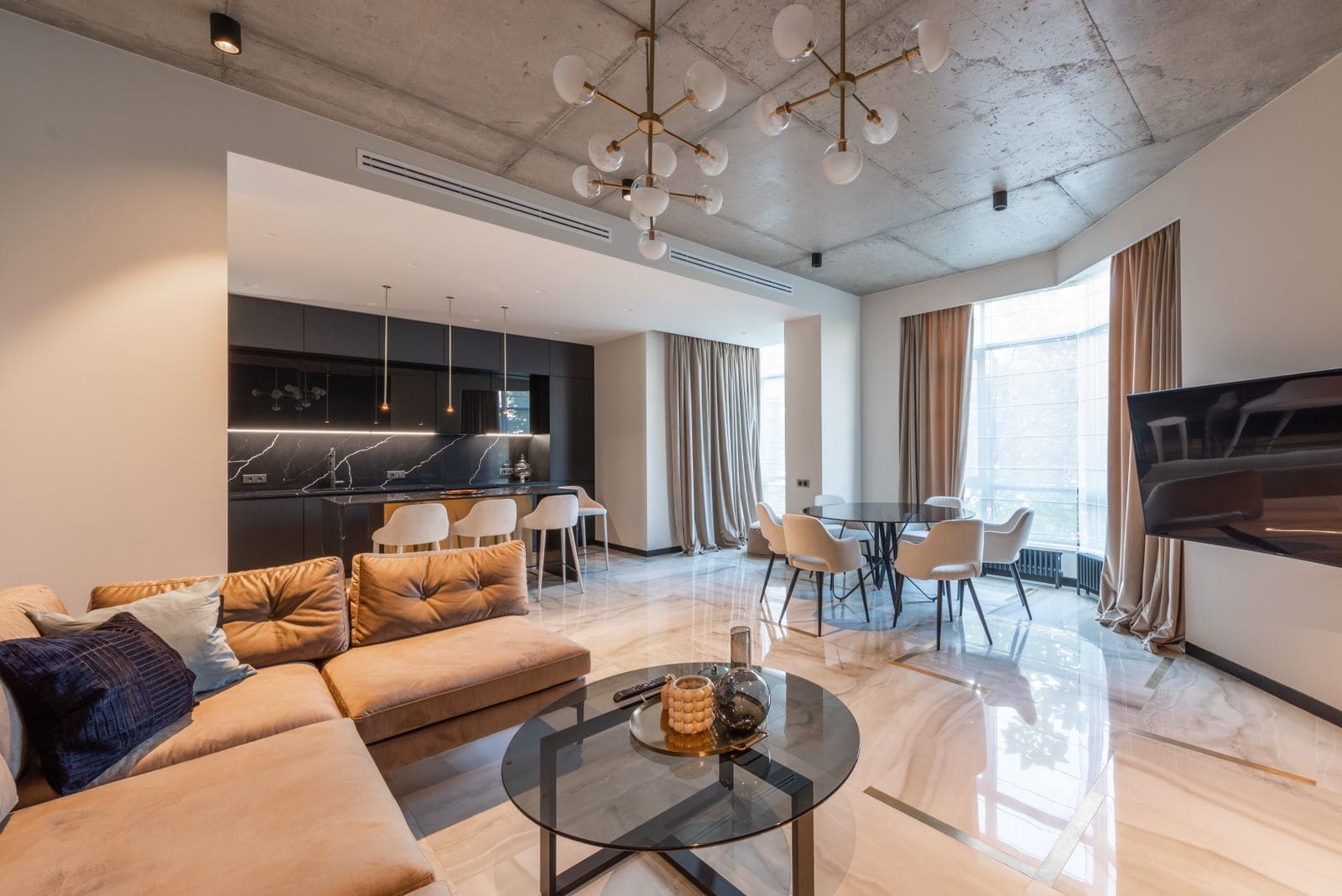 Studio apartment interior with a couch, dining table and open kitchen